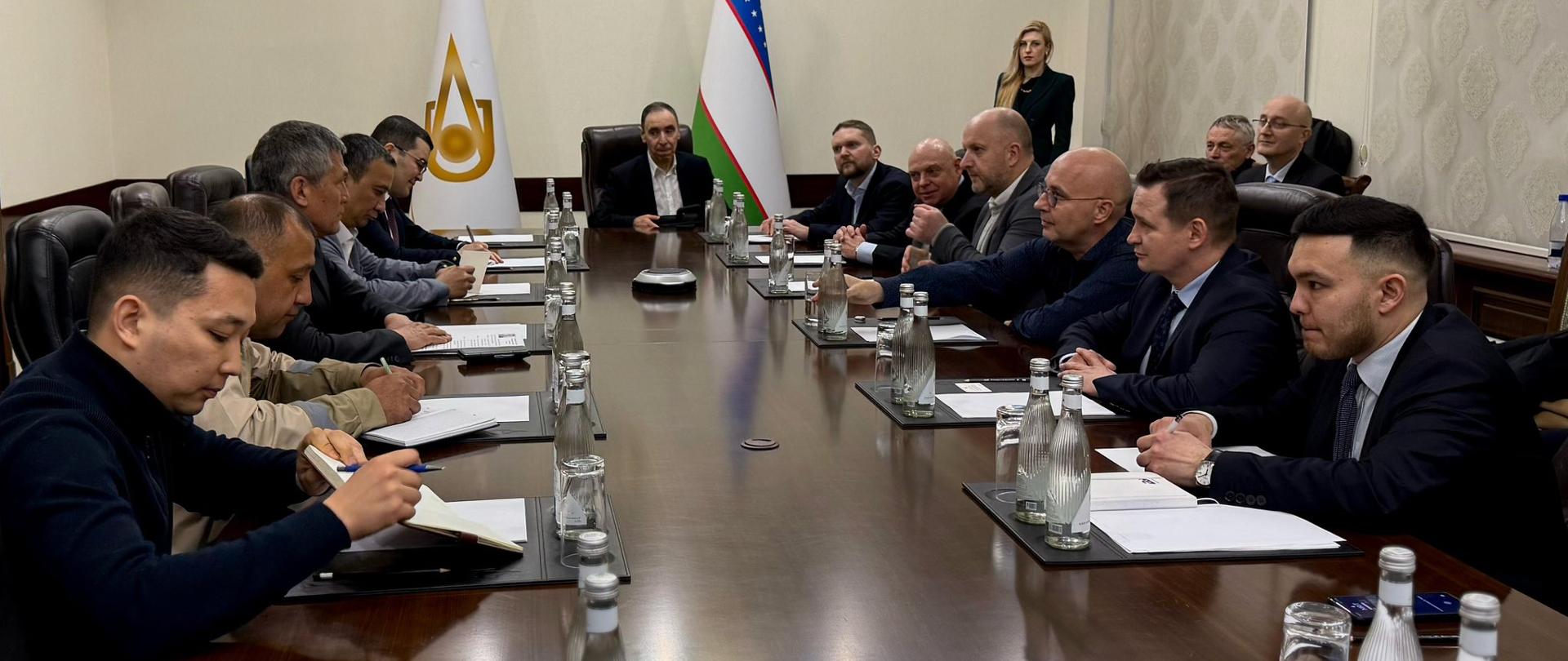 Z lewej strony stołu przedstawiciele Uzbekistanu, z prawej strony delegacja polska. Na wprost dwie flagi. 