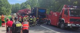 Akcja służb ratunkowych na miejscu wypadku koło Ostródy. Strażacy za pomocą specjalistycznego sprzętu uwalniają poszkodowanego kierowcę-operatora dźwigu samochodowego. Droga krajowa jest całkowicie nieprzejezdna.
