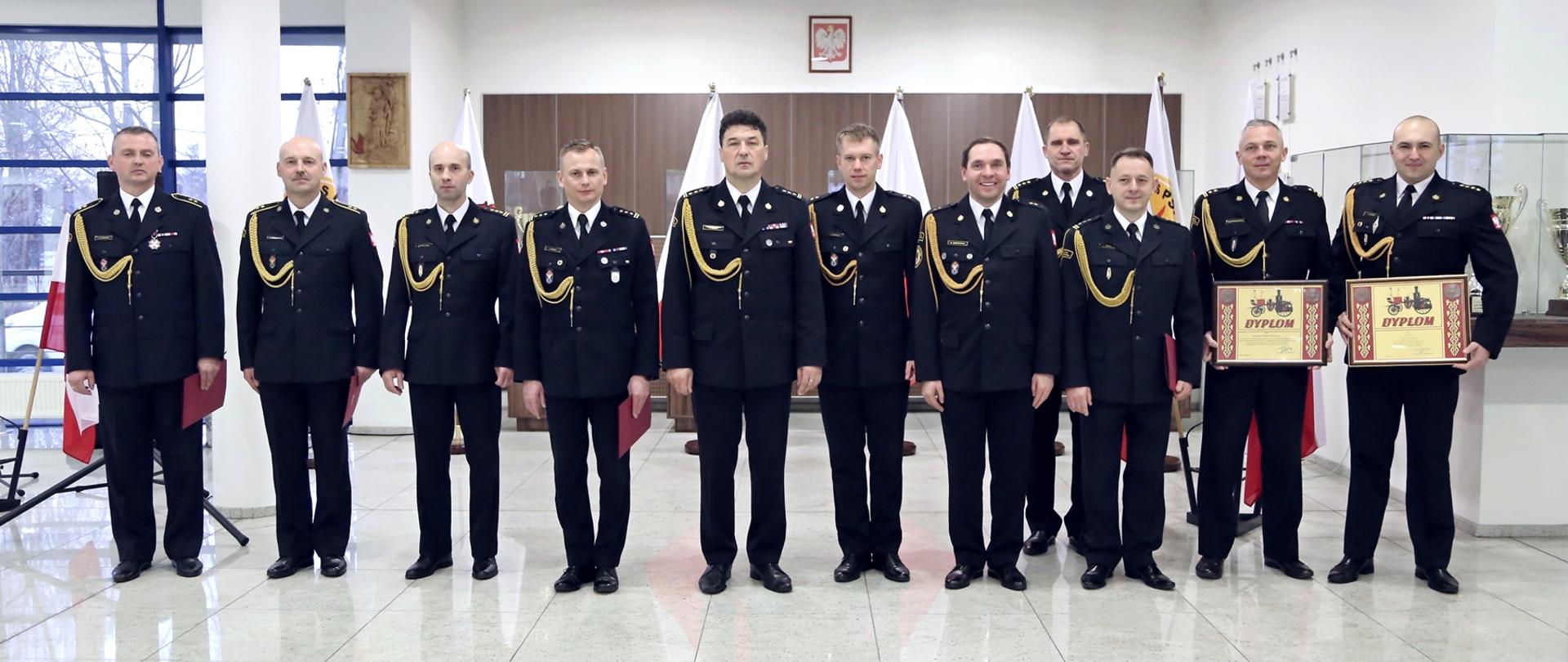 Grupowe zdjęcie awansowanych i nagrodzonych funkcjonariuszy CS PSP (9 osób) w towarzystwie Komendanta CS PSP oraz Zastępcy Komendanta CS PSP