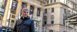 Minister rozwoju i technologii Piotr Nowak przed budynkiem Nowojorskiej Giełdy Papierów Wartościowych, za plecami ministra rusztowania na budynku giełdy 