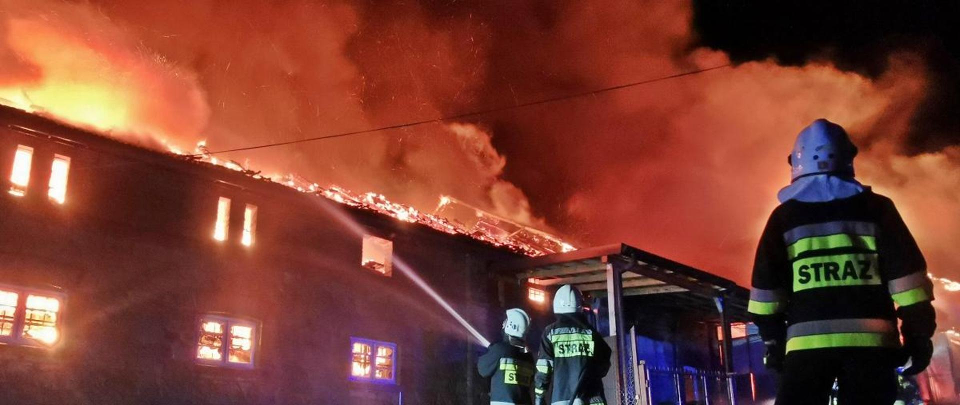 Zdjęcie płonącej hali oraz strażaków gaszących pożar