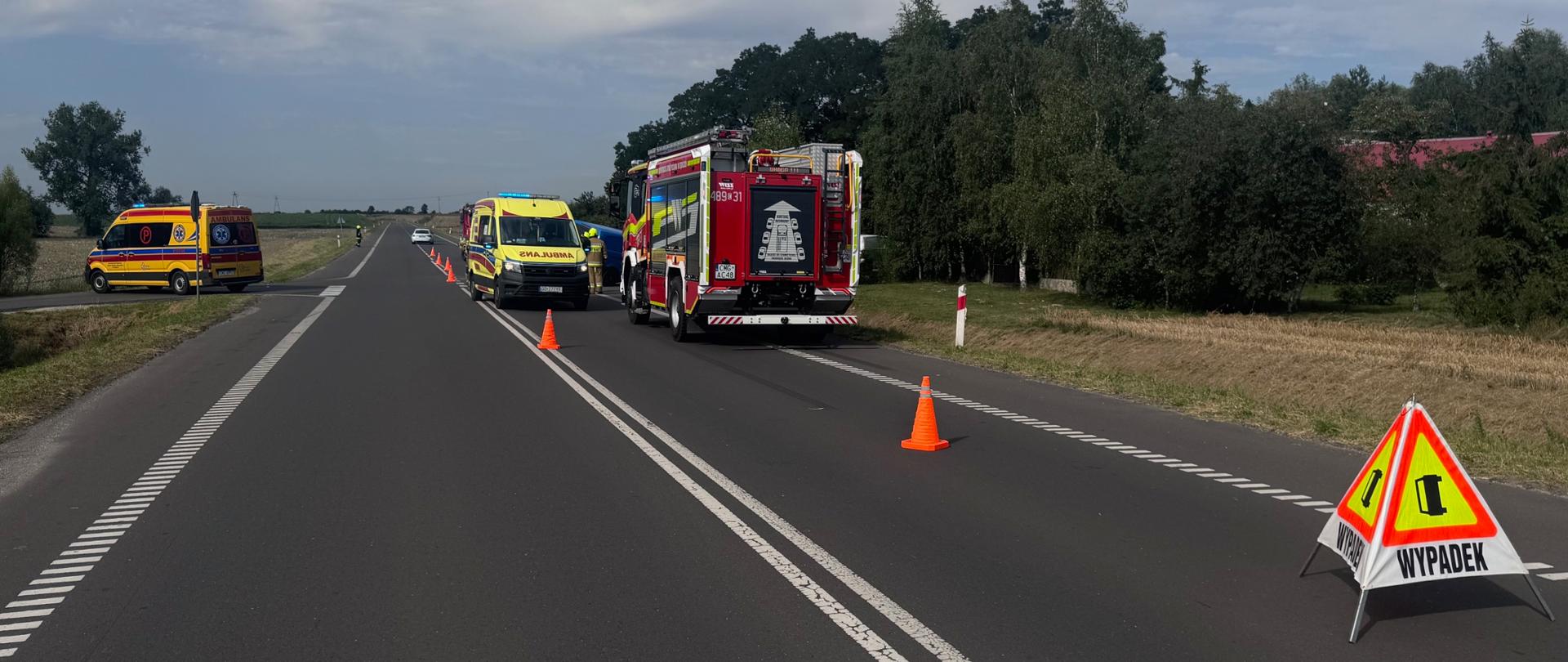 Na zdjęciu widoczne są pojazdy po zdarzeniu, służby ratunkowe oraz oznaczenia miejsca zdarzenia.