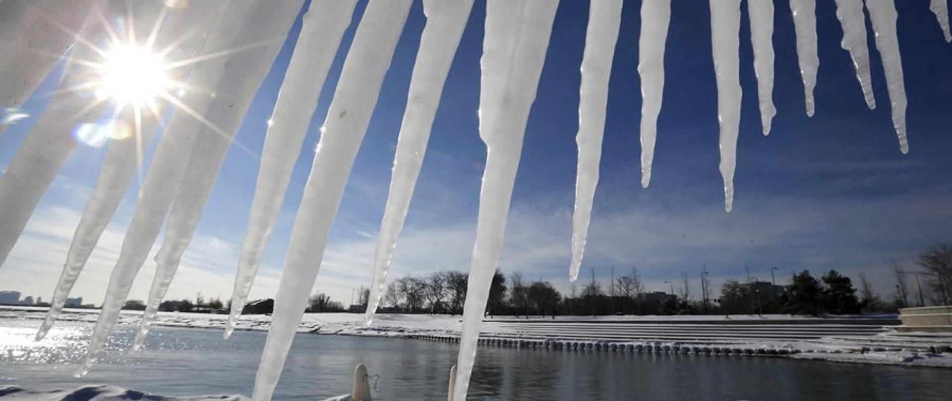 zdjęcie sopli zwisających z dachu w tle zbiornik wodny 