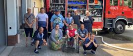 Na zdjęciu znajdują się podopieczni Środowiskowego Domu Samopomocy na tle samochodu strażackiego