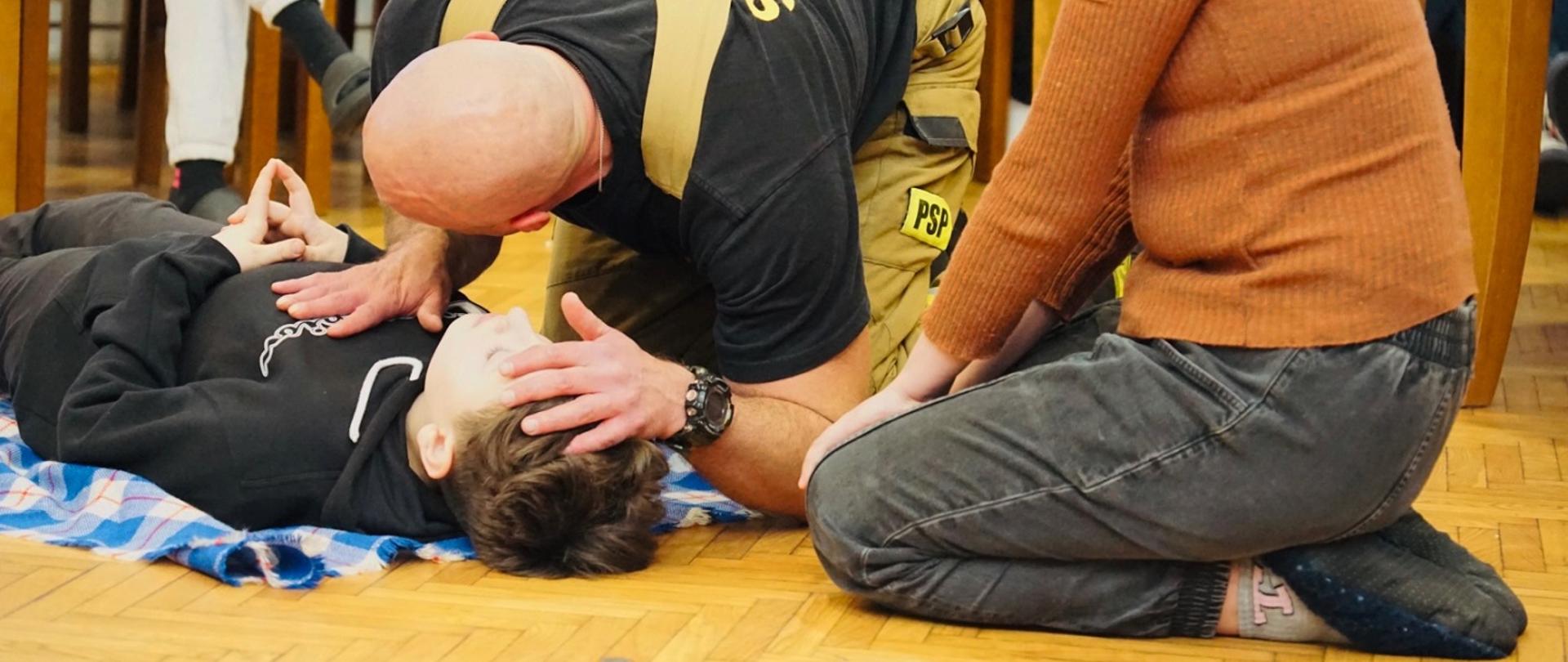 strażak uczy sprawdzania funkcji zyciowych dziewczynke 