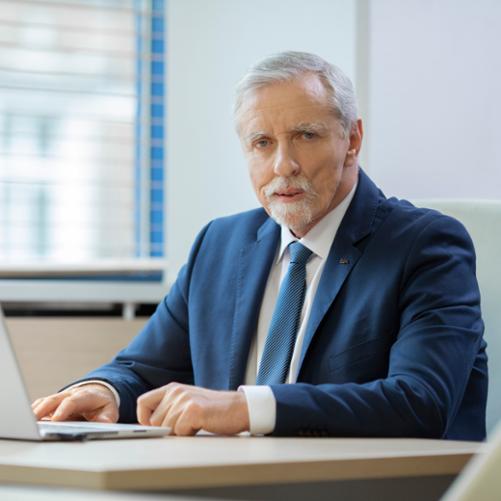 Elegancko ubrany mężczyzna siedzący za biurkiem