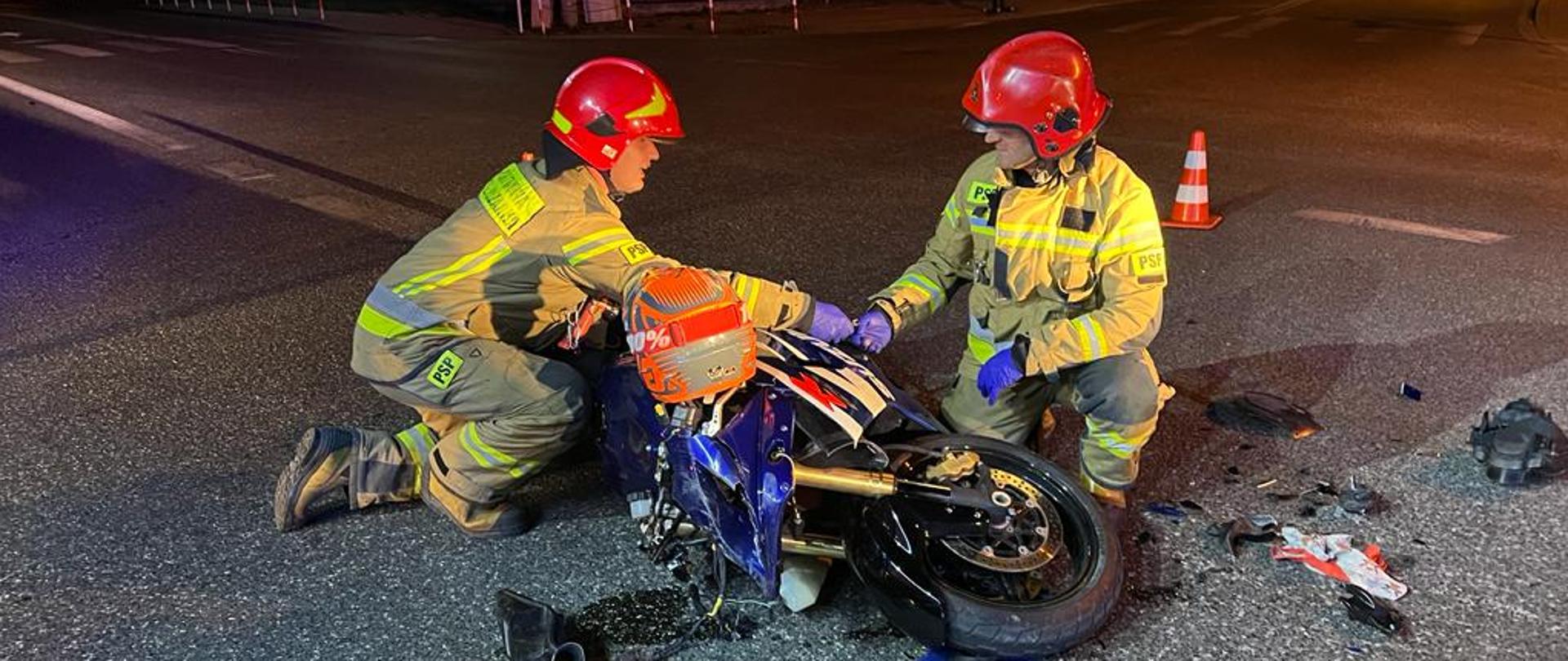 Strażacy prowadza czynności przy leżącym na drodze motocyklu