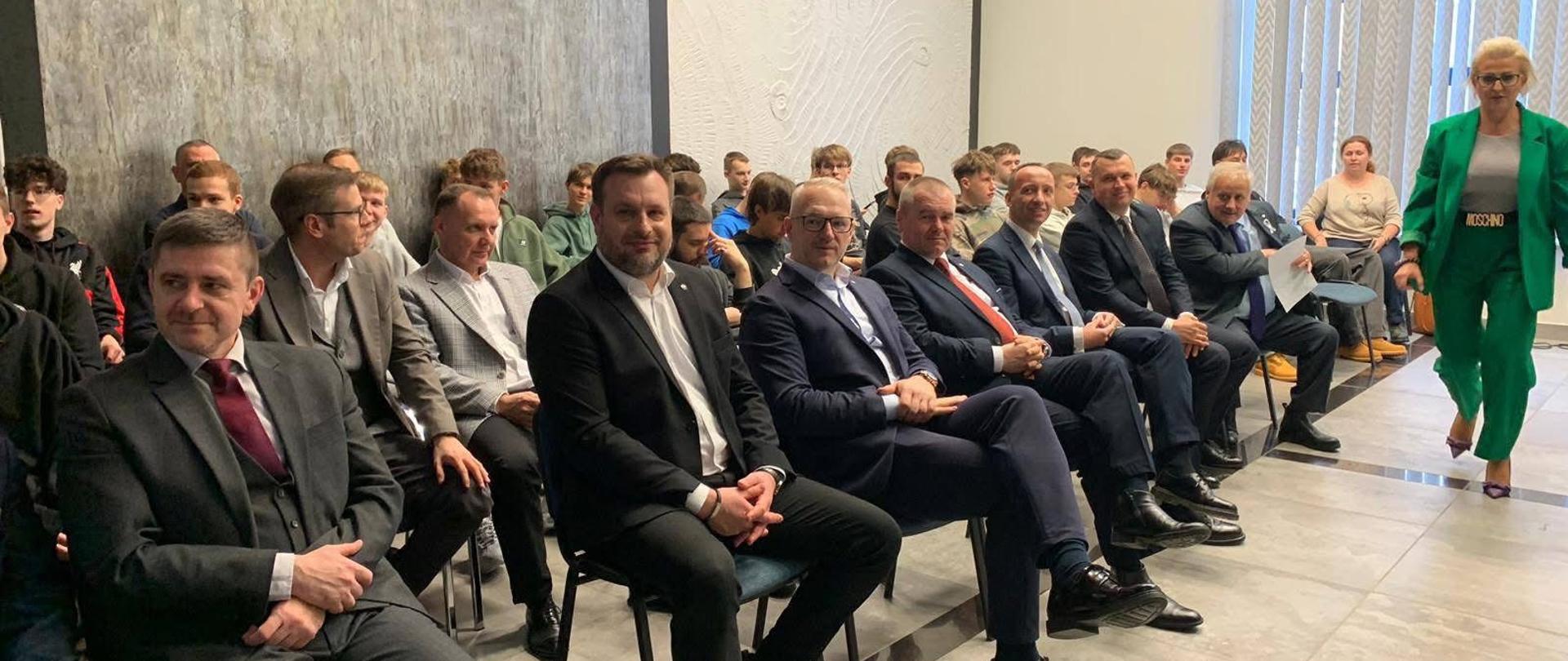 kilkanaście osób siedzi na sali 