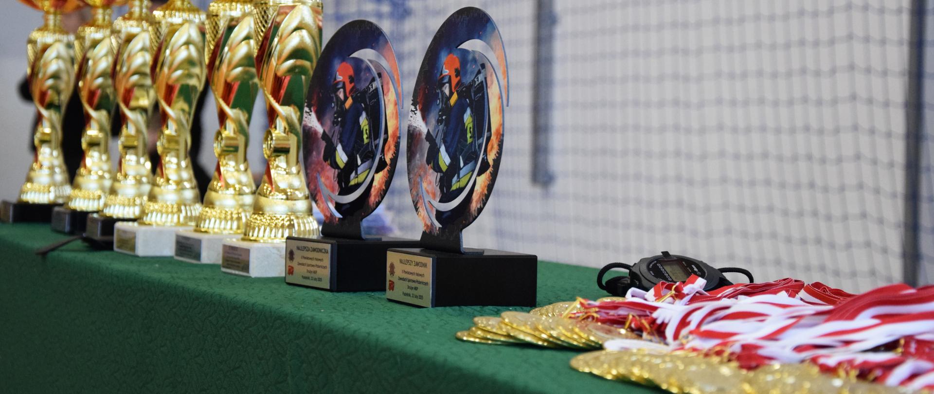 Puchary, statuetki oraz medale na zielonym płótnie