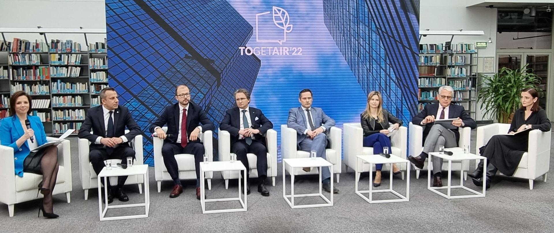 Grupa ludzi podczas konferencji siedząca na scenie i udzielająca wywiadu