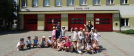 Zdjęcie przedstawia przedszkolaków z wychowawcami przed budynkiem Komendy Powiatowej Państwowej Straży Pożarnej w Wieluniu