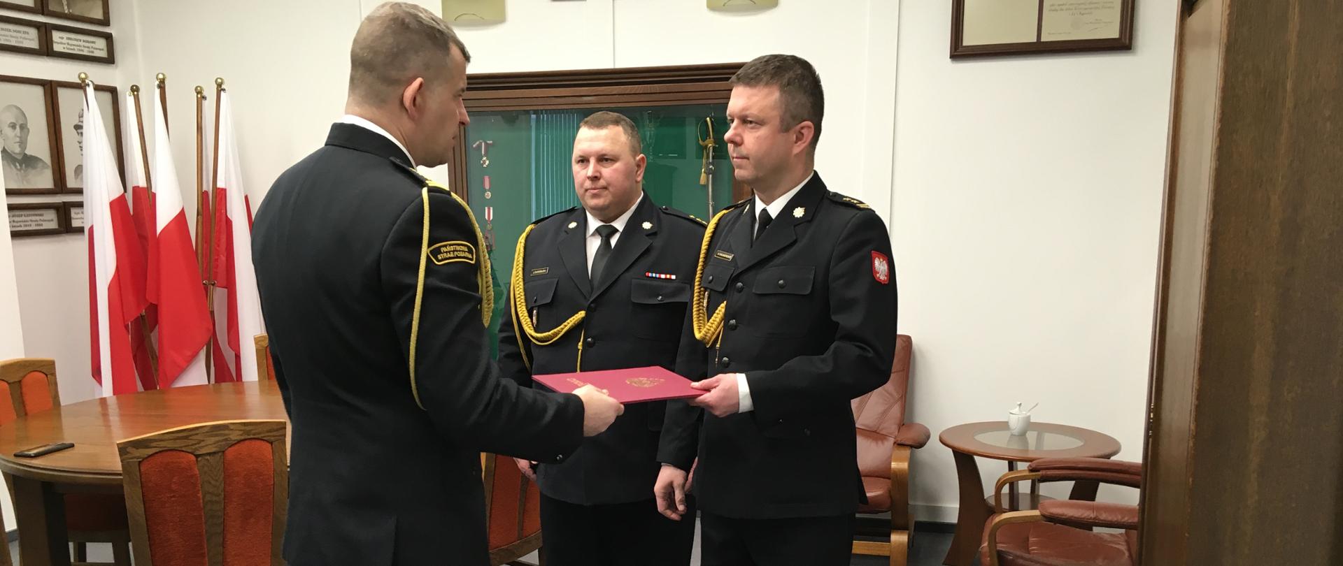 Komendant Wojewódzki PSP w Białymstoku przekazuje Adamowi Kalinowskiemu akt powołania na Zastępcę Komendanta Miejskiego w Łomży. Z boku Komendant Miejski PSP w Łomży kapitan Marek Bargielski