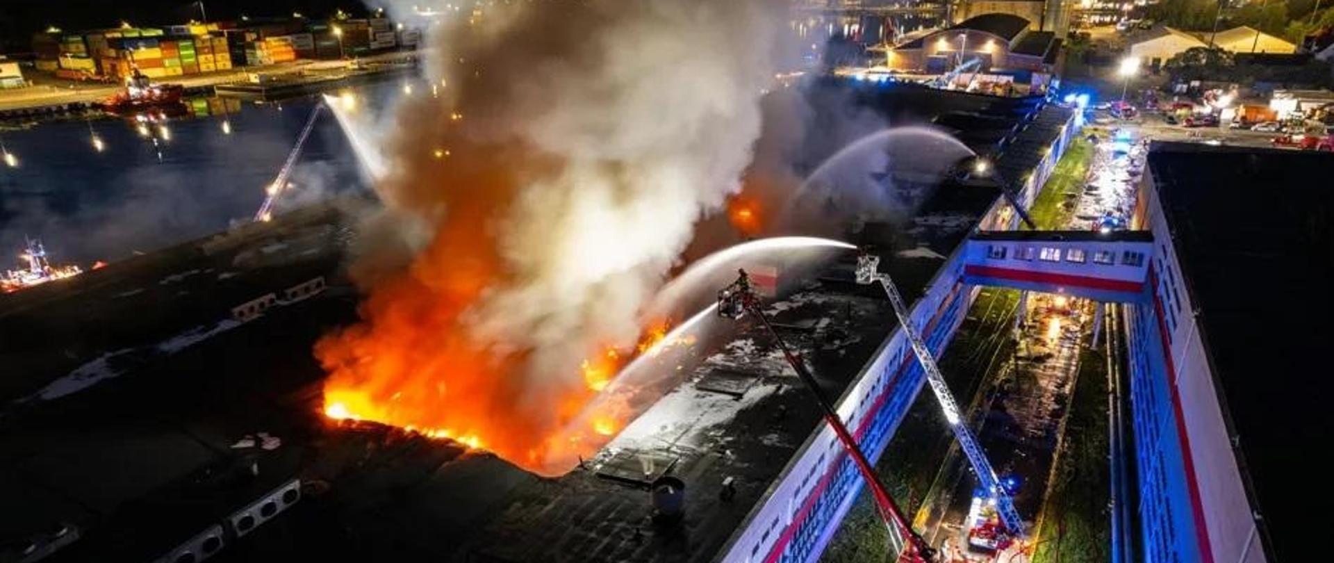 pożar hali, wozy strażackie, woda lejąca się na płomienie