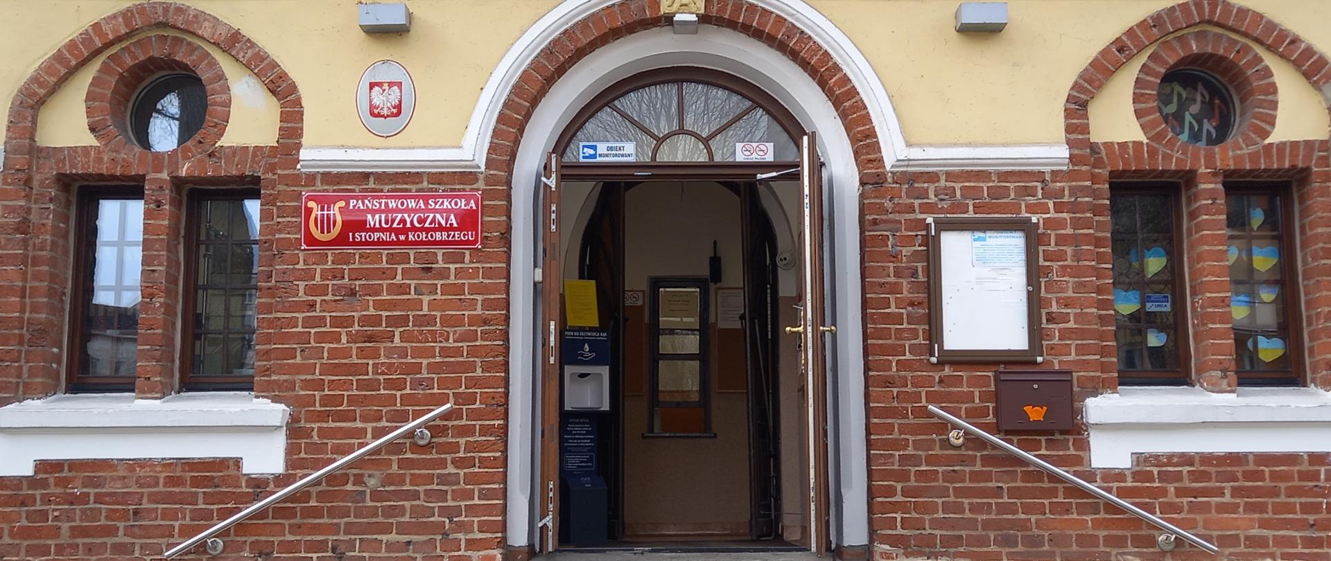 Zdjęcie przedstawiające elewację szkoły z otwartymi drzwiami