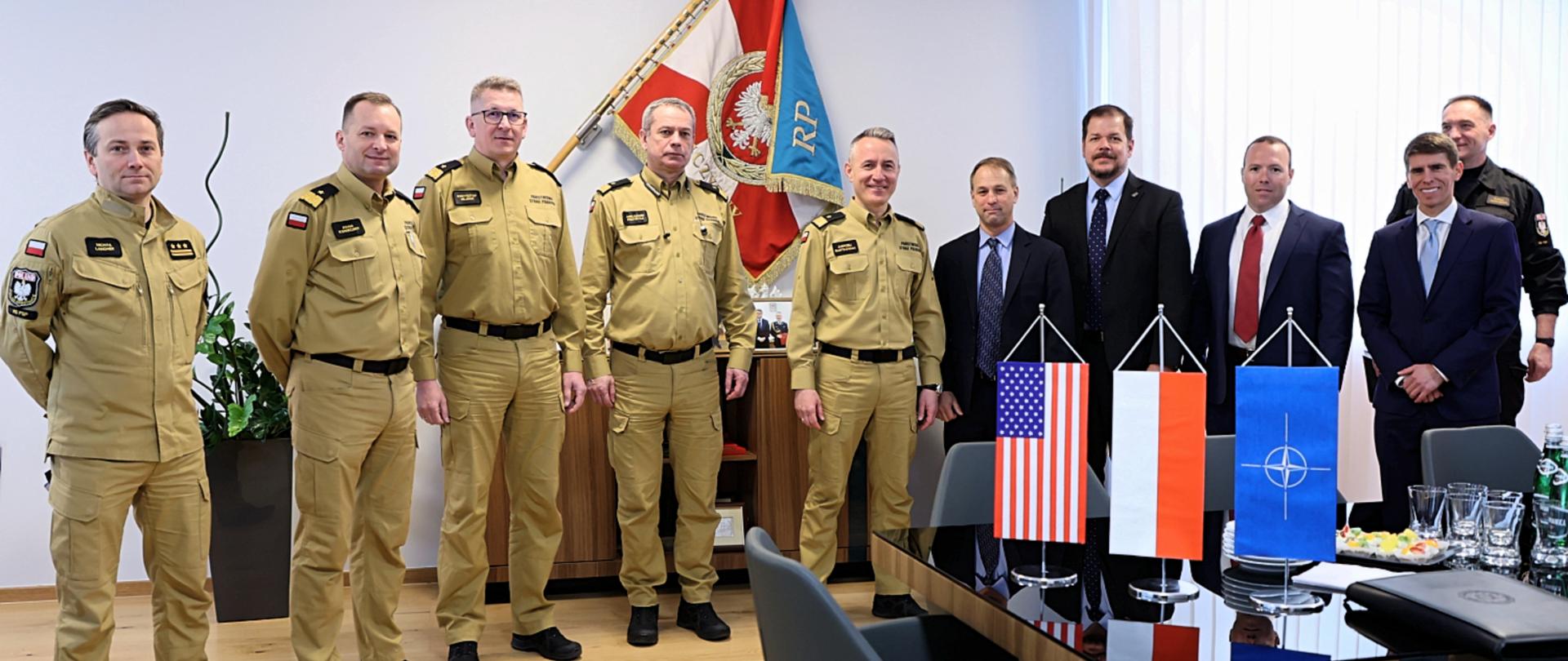 Na zdjęciu na tle sztandaru PSP znajdują się Komendant Główny PSP wraz z zastępcami i dyrektorem Planowania Operacyjnego oraz przedstawiciele FBI. 