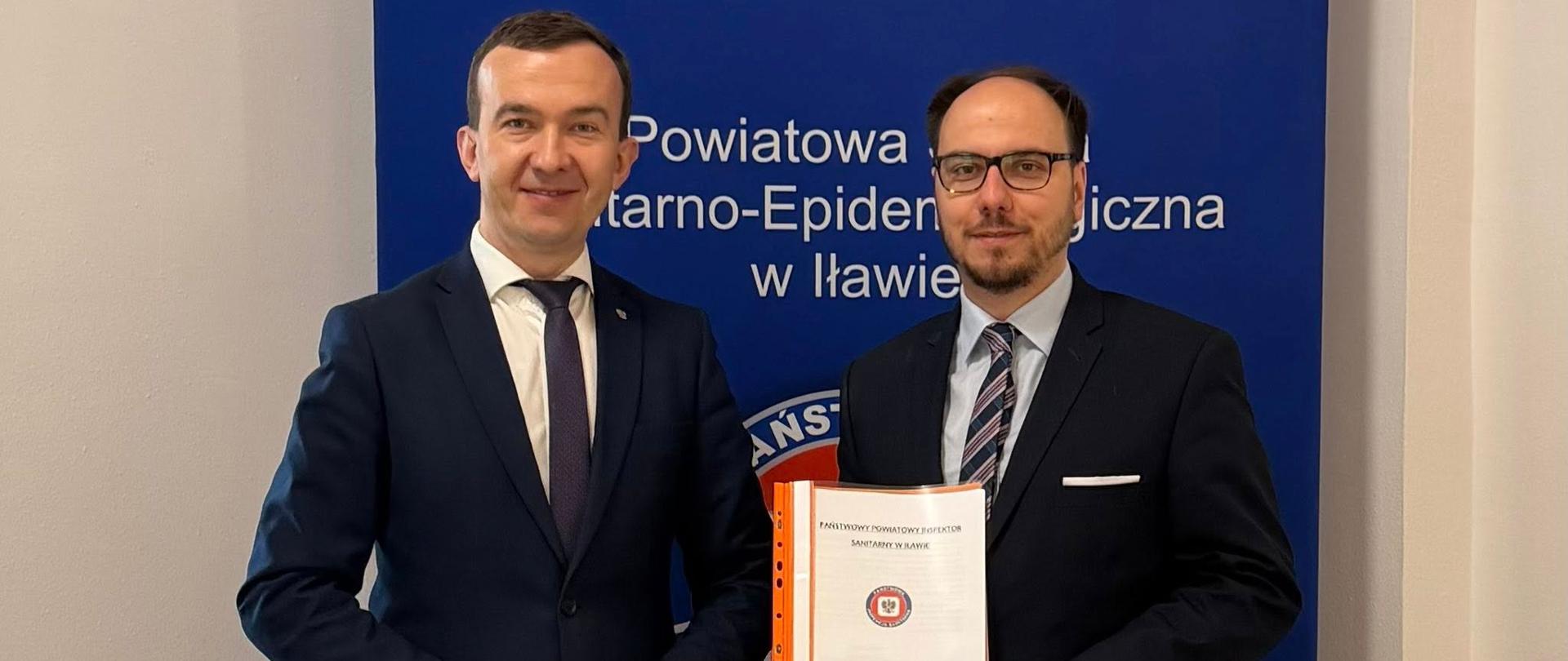 2 mężczyzn w garniturach, w tym wicewojewoda, pozują na tle ścianki Powiatowego Inspektoratu 