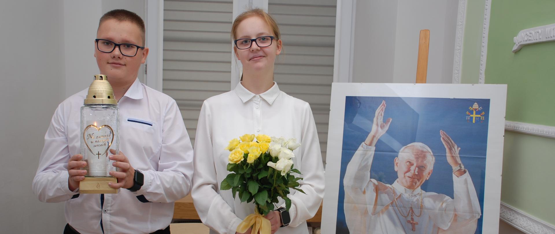 Uczniowie składają kwiaty i znicz pod obrazem Papieża Polaka 