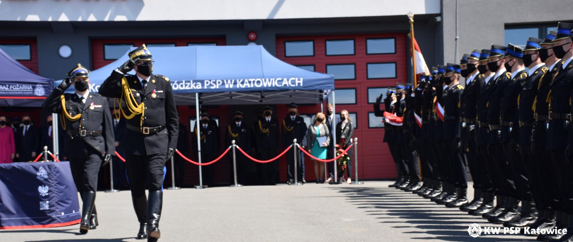 Na zdjęciu widoczny jest plac przed Komendą Powiatową PSP w Wodzisławiu Śląskim. Podczas uroczystości nadania sztandaru Komendzie Powiatowej PSP w Wodzisławiu Śląskim oraz Wojewódzkich Obchodów Dnia Strażaka. Zastępca komendanta głównego PSP nadbryg. Krzysztof Hejduk dokonuje przeglądu pododdziałów, w tle budynek komendy i stojący goście.