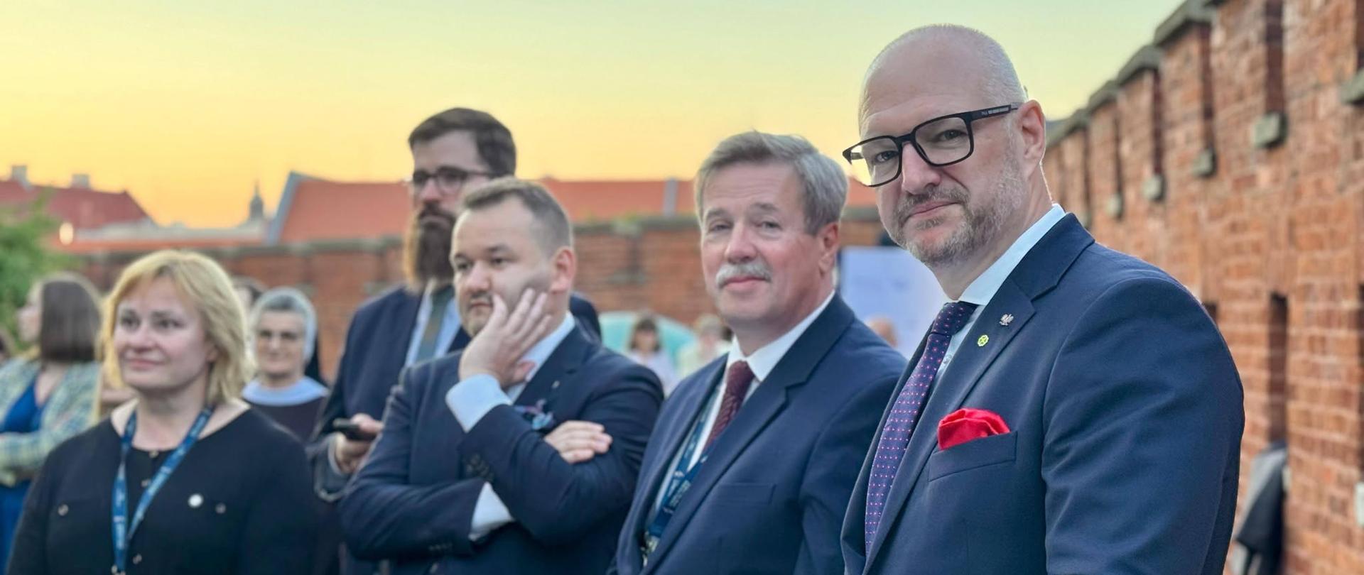 Kilka osób stoi przy okrągłym stoliku 