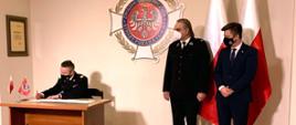 Zdjęcie przedstawia komendanta głównego PSP nabryg. Andrzeja Bartkowiaka podpisującego list intencyjny w obecności Michała Dworczyka, szefa Kancelarii Prezesa Rady Ministrów oraz dh. Waldemara Pawlaka prezesa ZG ZOSP RP.\n"