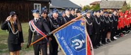 druhny i druhowie stoją w szyku ze sztandarem podczas uroczystości włączenia jednostki OSP Miejska Dąbrowa oraz OSP Zajezierze do Krajowego Systemu Ratowniczo-Gaśniczego oraz przekazania nowego średniego samochodu ratowniczo-gaśniczego dla OSP Gniewoszów.