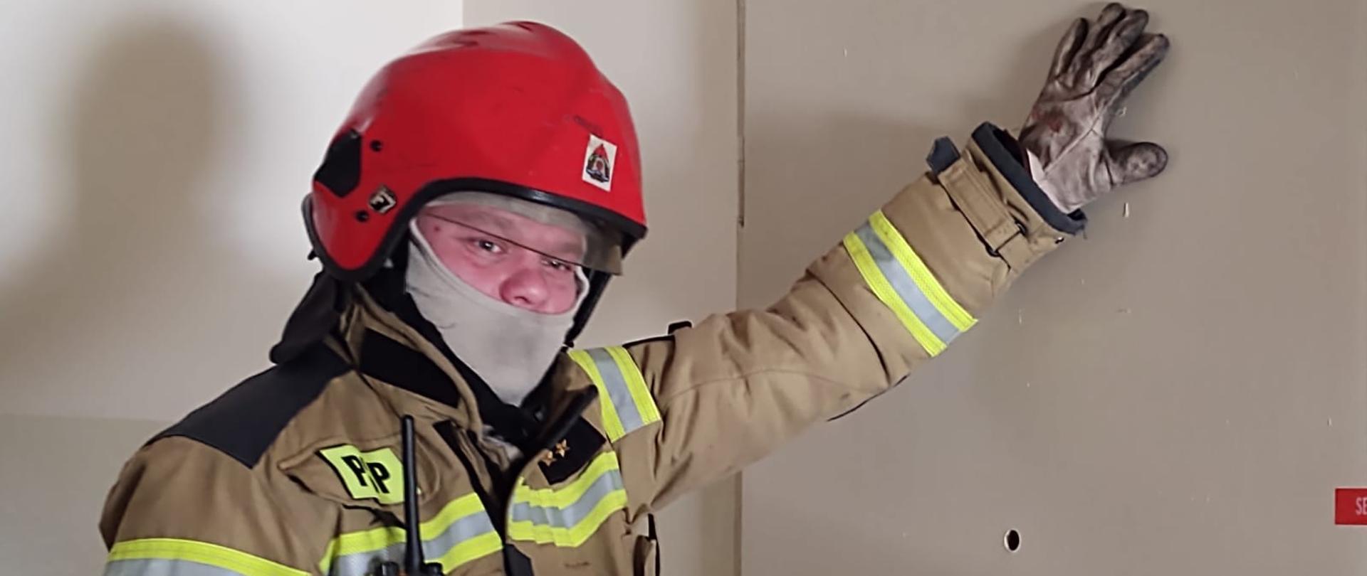 Strażak dotyka drzwi sprawdzając temperaturę.