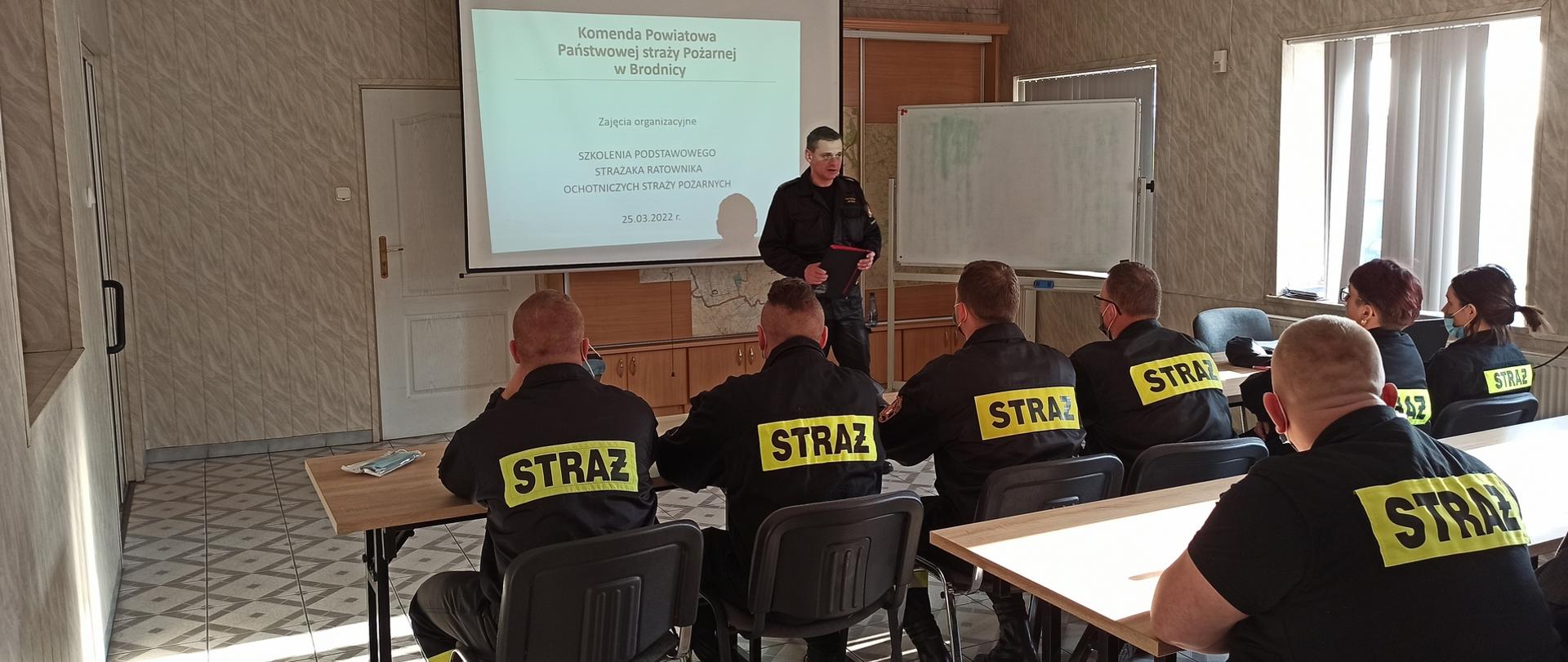 Zdjęcie przedstawia Zastępcę Komendanta Powiatowego PSP w Brodnicy kpt. Krzysztofa Natuckiego otwierającego szkolenie podstawowe strażaków ratowników OSP. Na pierwszym planie siedzący druhowie ochotnicy.