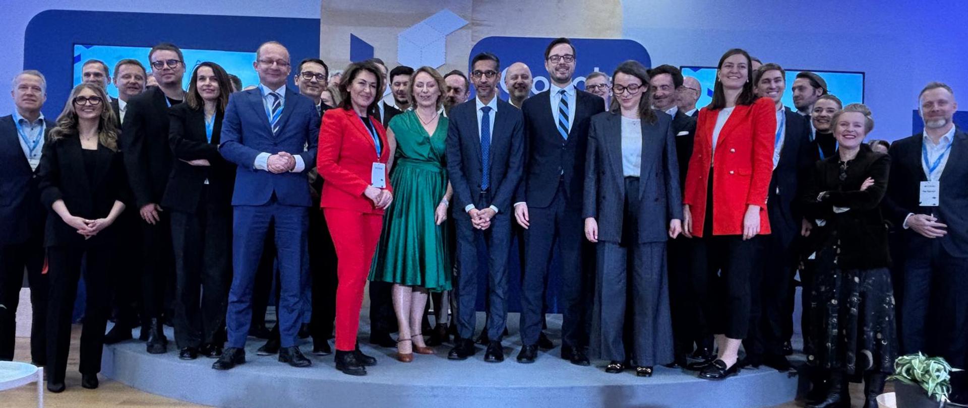 Family photo. Uczestnicy spotkania stoją na scenie. W tle ścianki.