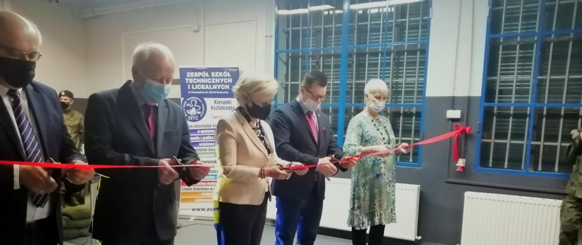 podczas uroczystości otwarcia strzelnicy wiceminister Marzena Machałek wraz z innymi uczestnikami spotkania przecina wstęgę