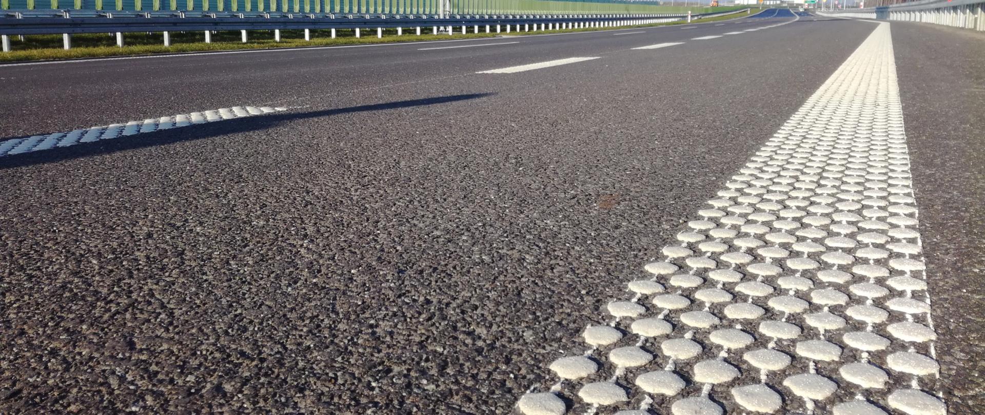 Zdjęcie przedstawia poglądowo drogę ekspresową w oddali. Widok z poziomu drogi.