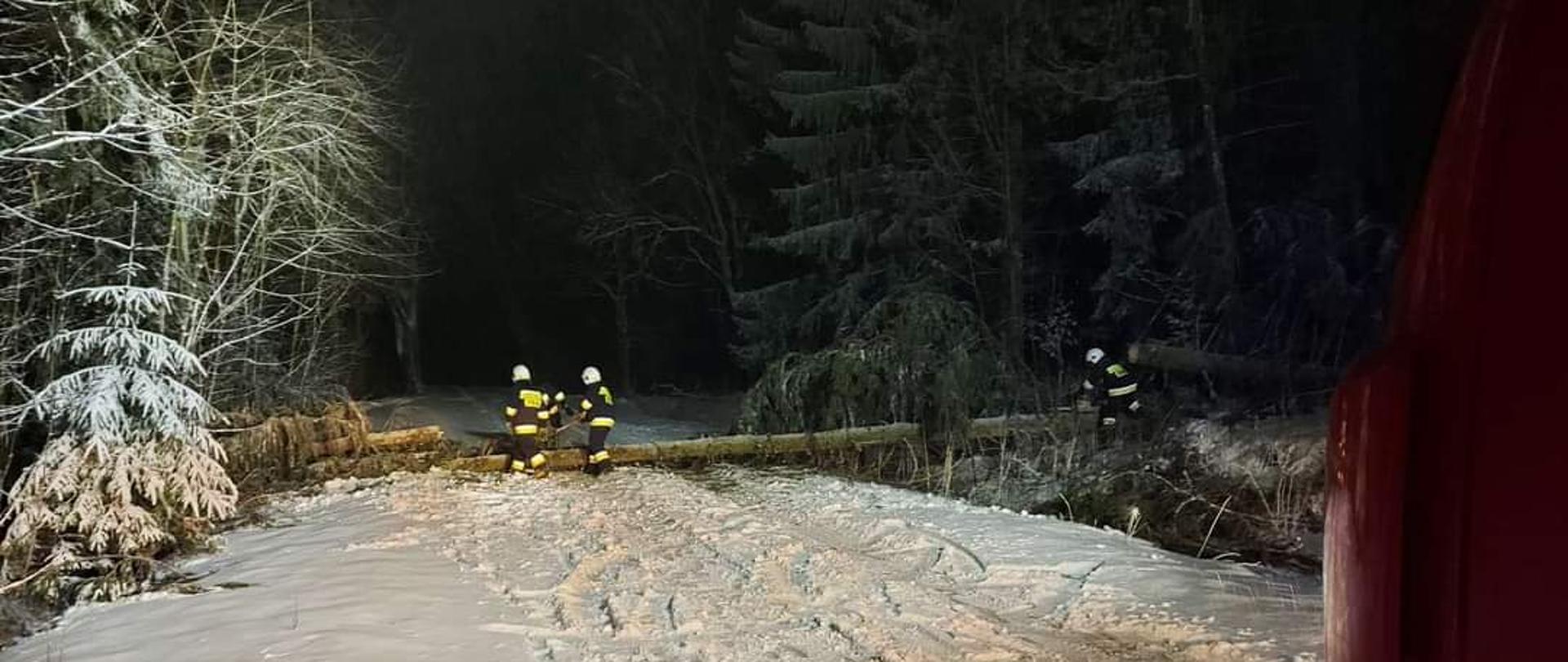 Zdjęcie przedstawia strażaków Ochotniczej Straży Pożarnej w Górnem podczas działań ratowniczych dotyczących usuwania drzewa (powalonego przez silne porywy wiatru) z drogi publicznej