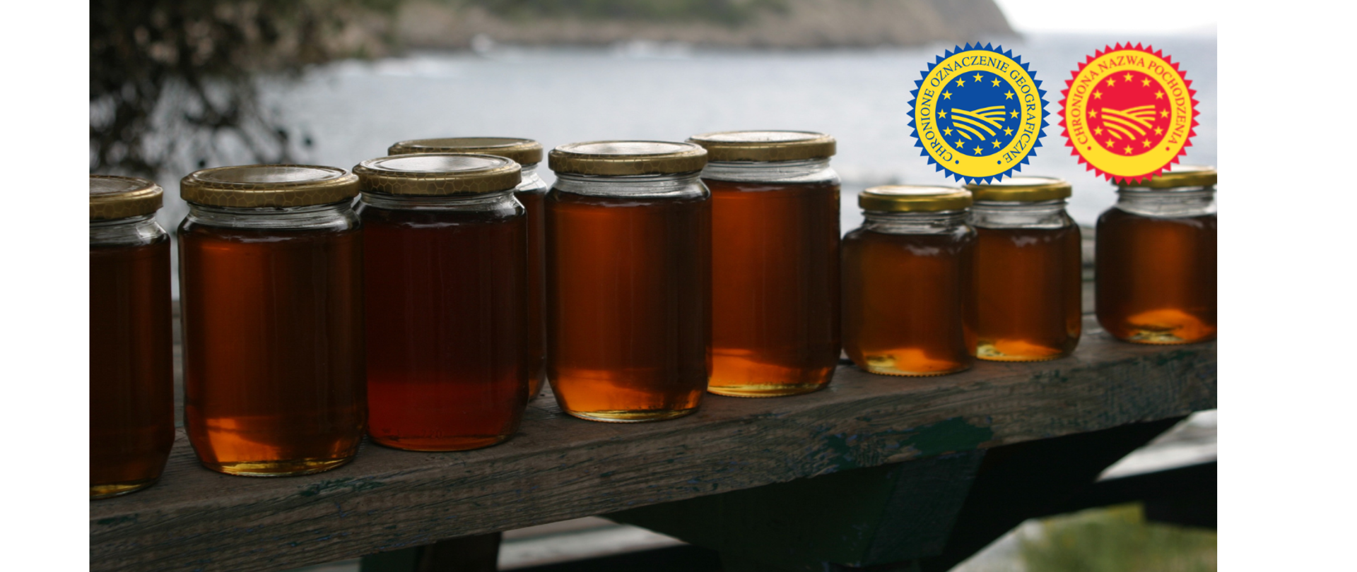 Słoiki miodu z różną pojemnością na drewnianej ławce na tle jeziora 