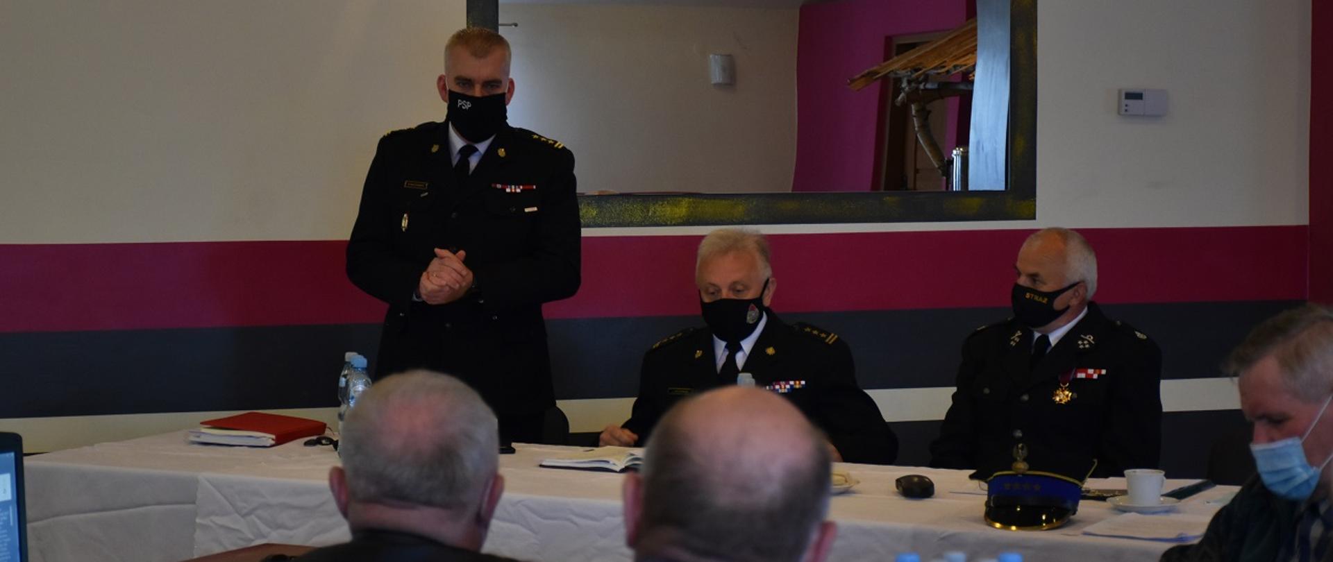 Na zdjęciu przy stoliku widzimy st. bryg. Marcina Machowskiego Komendanta Powiatowego PSP w Skarżysku-Kamiennej, Zastępcę Świętokrzyskiego Komendanta Wojewódzkiego PSP w Kielcach st. bryg. Jarosław Piotrowski oraz druha Andrzeja Markiewicza Prezesa Ochotniczej Straż Pożarnej w Skarżysku-Kamiennej. Komendant Powiatowy jako pierwszy zabrał głos otwierając spotkanie dotyczące konsultacji projektu ustawy o ochotniczych strażach pożarnych. 