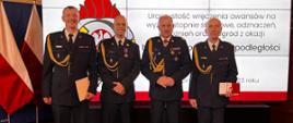 Zdjęcie przedstawia 4 strażaków podczas Uroczystość wręczenia awansów na wyższe stopnie służbowe, odznaczeń, wyróżnień oraz nagród