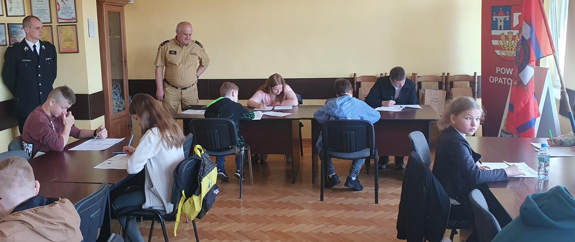 Zdjęcie przedstawia uczestników konkursu OTWP podczas testu pisemnego. W tle komisja egzaminacyjna.