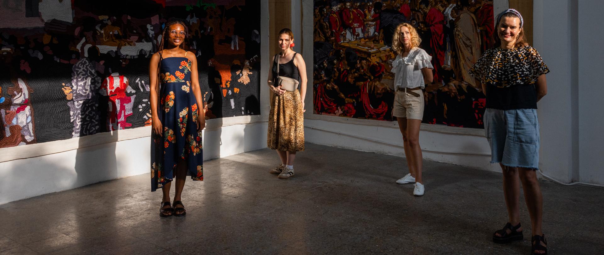Four artists in front of tapestries.