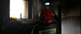 Strażak we wnętrzu spalonego pomieszczenia z kamerą termowizyjną