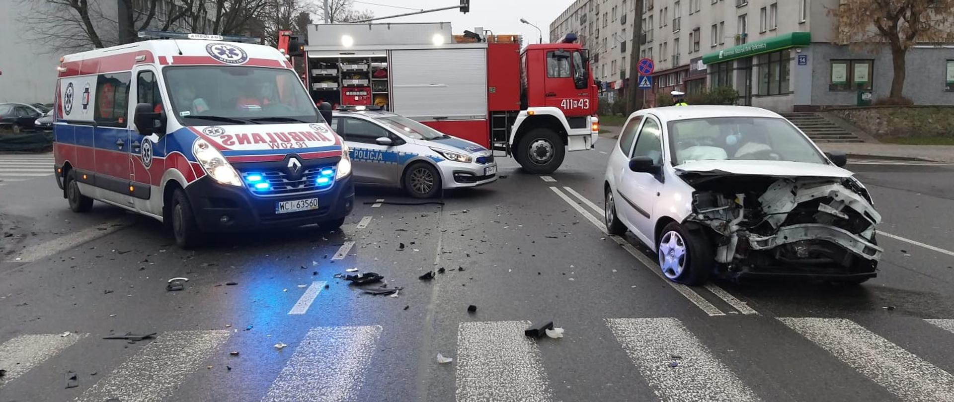Na zdjęciu rozbity samochód osobowy. Na drugim planie widoczny jest ambulans ZRM oraz radiowóz Policji. Ostatni na planie samochód ratownictwa technicznego Straży Pożarnej w Ciechanoiwie