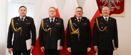 Na tle flag i godła stoją kolejno od lewej: nowy zastępca łódzkiego komendanta wojewódzkiego, łódzki komendant wojewódzki, zastępca komendanta głównego oraz ustępujący zastępca wojewódzki w Łodzi