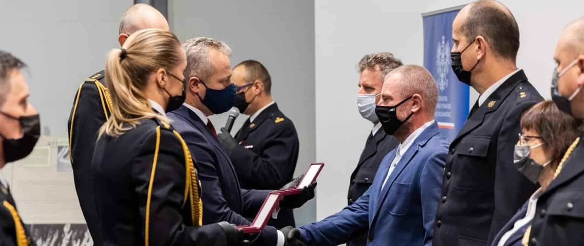 Po stronie prawej Wojewoda Kujawsko-Pomorski wręcza medale i odznaczeniu osobom ustawionych w szeregu stojącym na przeciwko. 