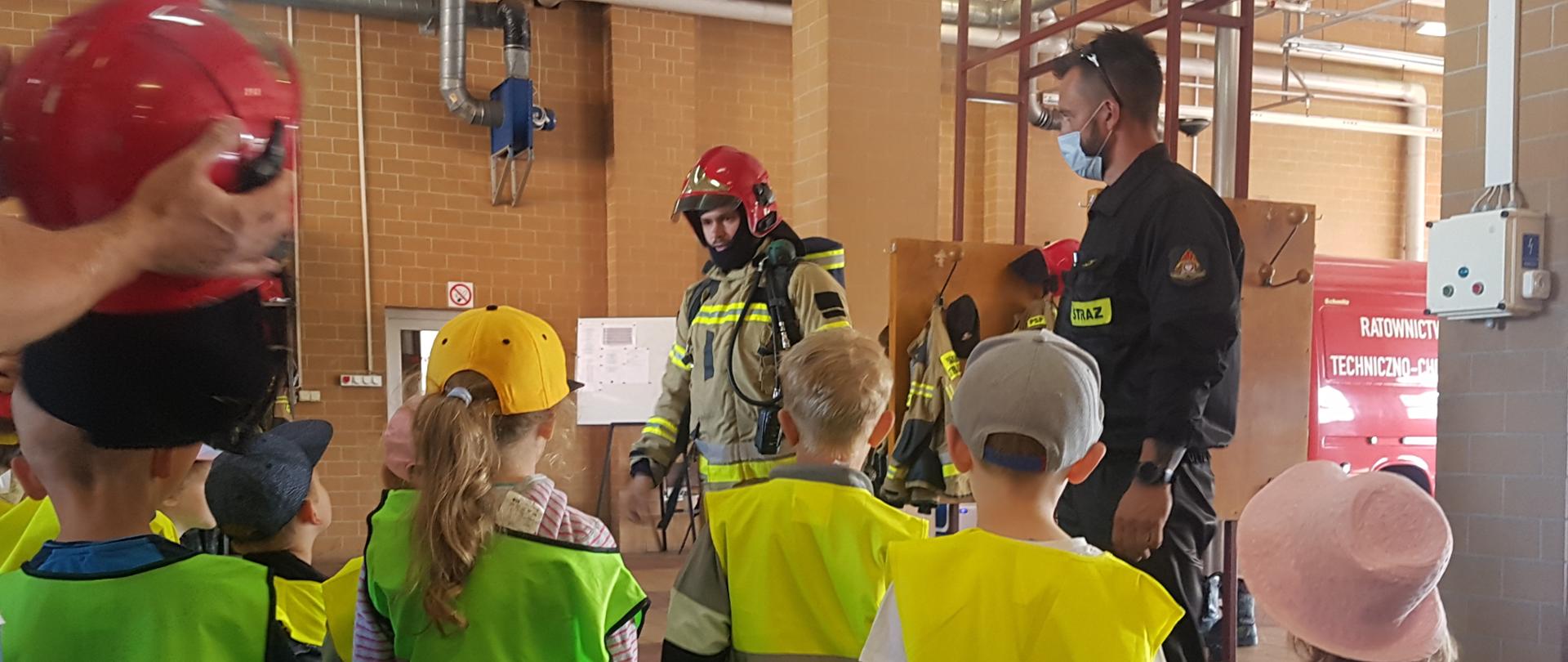 Wnętrze garażu, grupa dzieci, dwóch strażaków