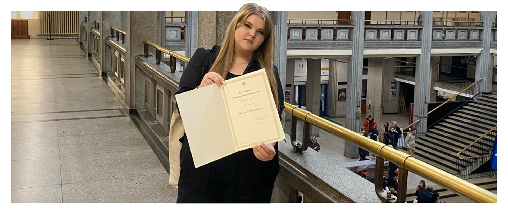 Hanna Kęska prezentująca dyplom dla stypendysty Prezesa Rady Ministrów otrzymanego w Auli Głównej Szkoły Głównej Handlowej w Warszawie