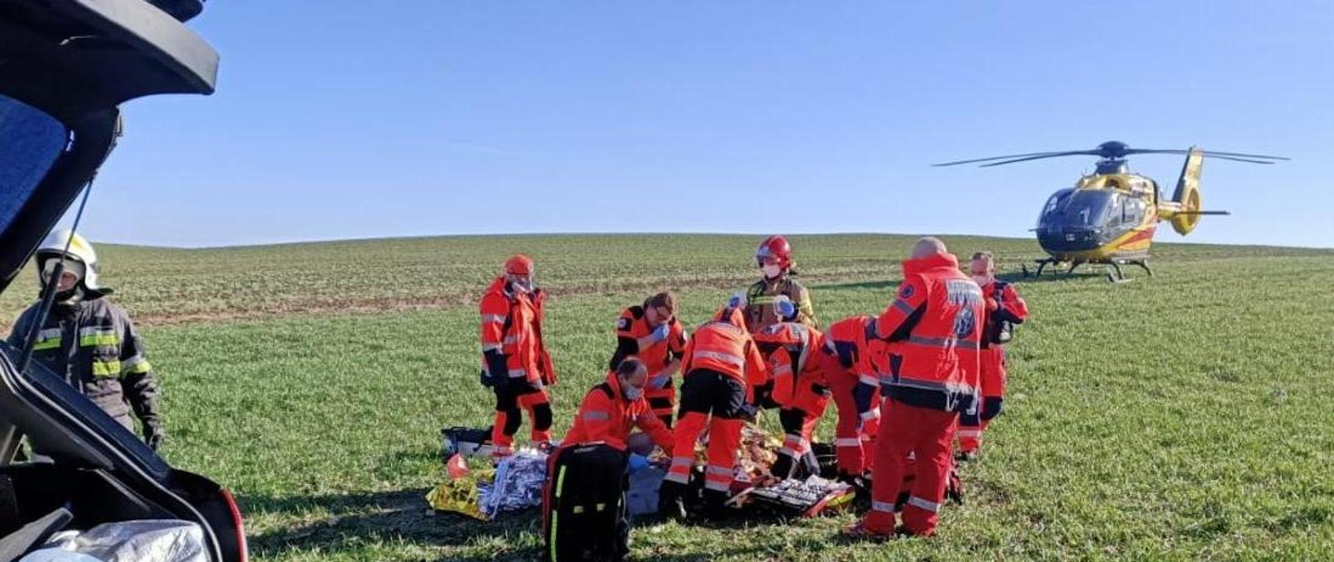 Strażacy na polu, w głębi śmigłowiec