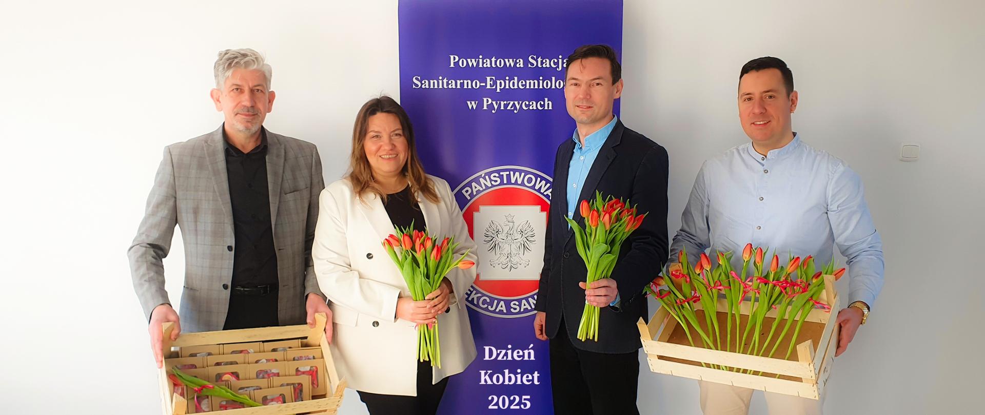 Obraz przedstawia Dzień Kobiet w Powiatowej Stacji Sanitarno-Epidemiologicznej w Pyrzycach. Męska część pracowników Stacji z Państwowym Powiatowym Inspektorem w Pyrzycach na czele ze skromnymi upominkami i kwiatkami wszystkich Pań. W tle baner PSSE w Pyrzycach