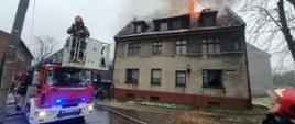 Samochód straży pożarnej przed budynkiem, w którym płonie dach