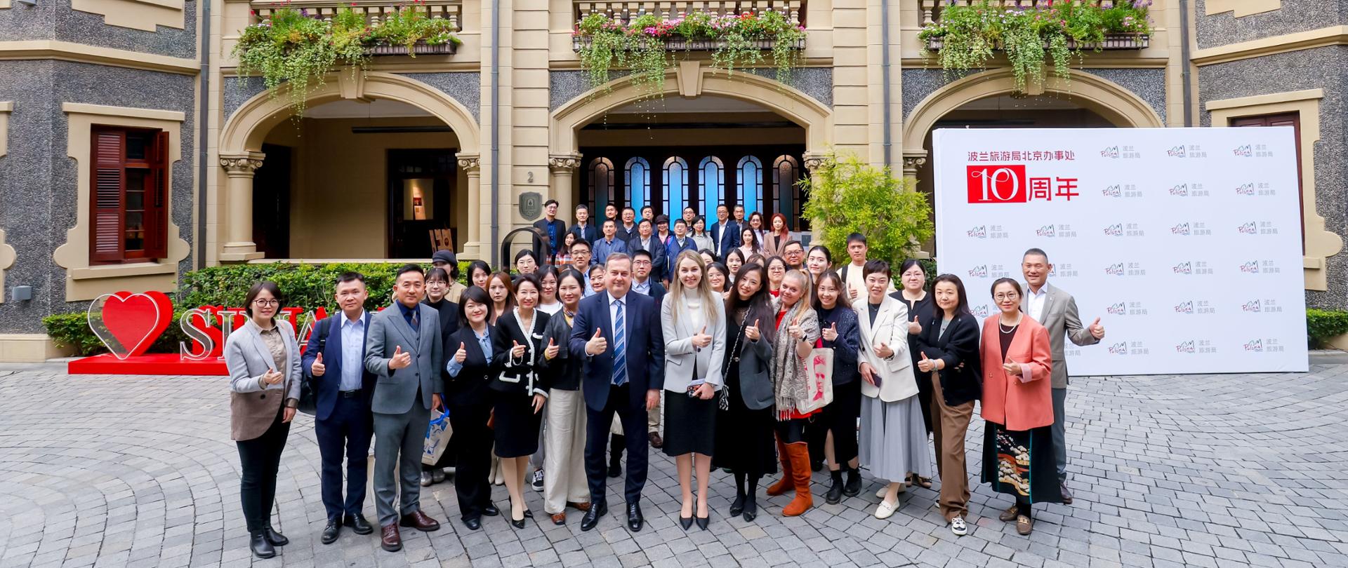 Duża grupa ludzi stoi pod budynkiem