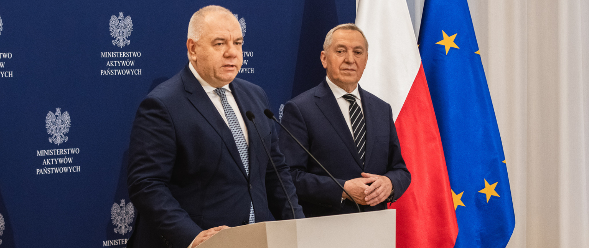 Wicepremier Jacek Sasin i wicepremier, minister rolnictwa i rozwoju wsi Henryk Kowalczyk, bliski plan. W tle ścianka z logotypami MAP i flagi. 