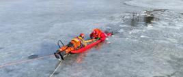 Strażak na saniach lodowych podejmuje poszkodowanego