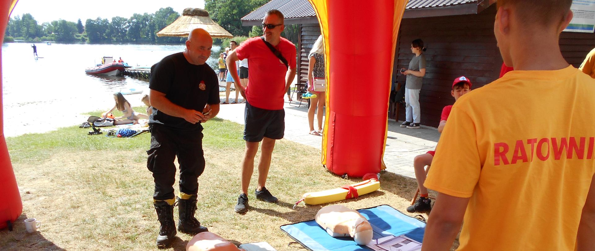 Ratownicy na plaży pod namiotem. Na ziemi rozstawione fantomy ćwiczebne.