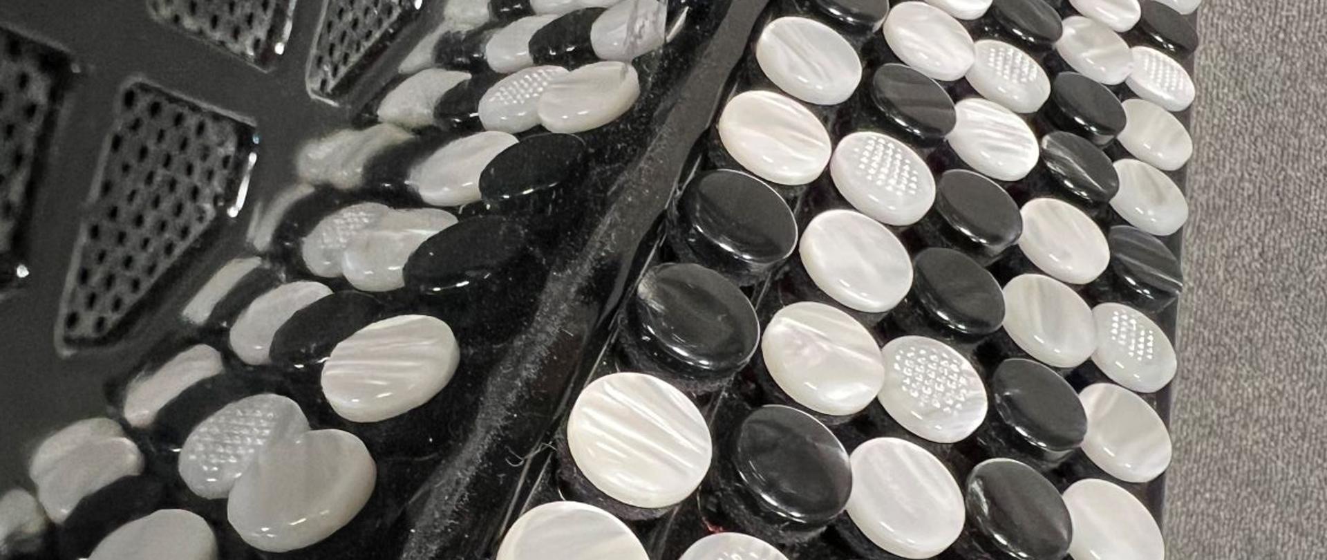 Zdjęcie przedstawia prawą stronę akordeonu guzikowego i fragment galeryjki